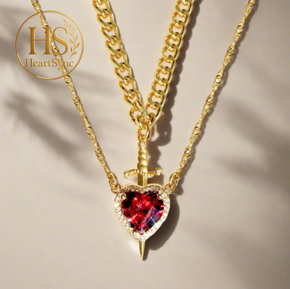 Necklace product shot: Heart & Sword pendant on gold chain, featuring a red stone heart & sword design. HeartSync logo