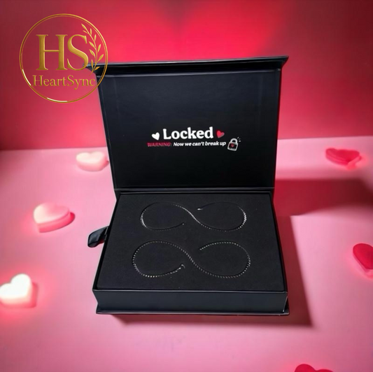 Open box of "We Locked" permanent bracelets, with infinity design. Text: "WARNING: Now we can't break up." Valentine's gift